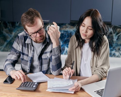 A diverse Canadian family thoughtfully discussing household budgeting and checking physical planning files at home